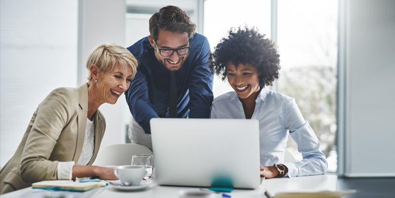 3 happy office workers overseeing training content on a laptop
